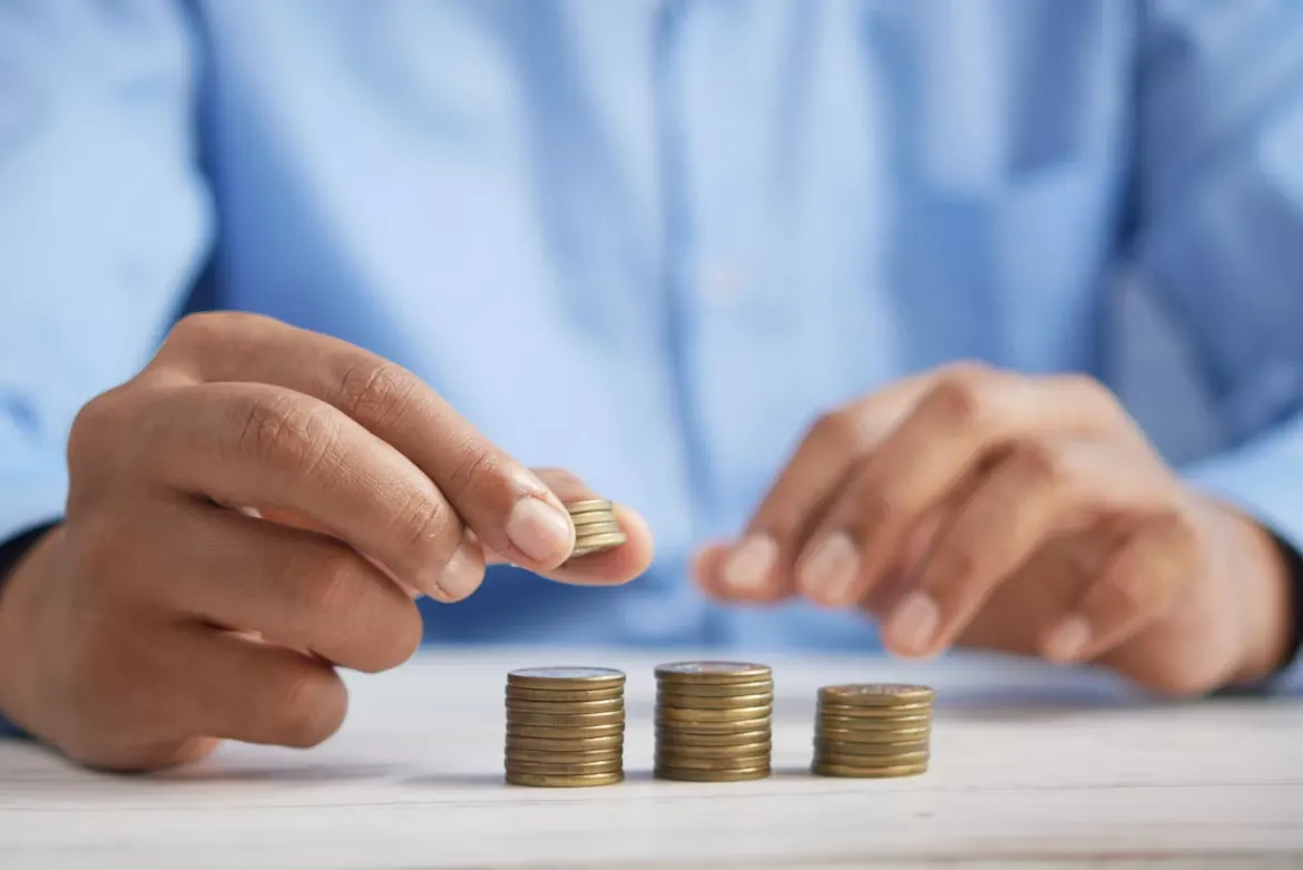 Hands stacking coins into small piles on a table